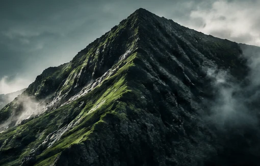 A misty green mountain ridge rising through low clouds.
